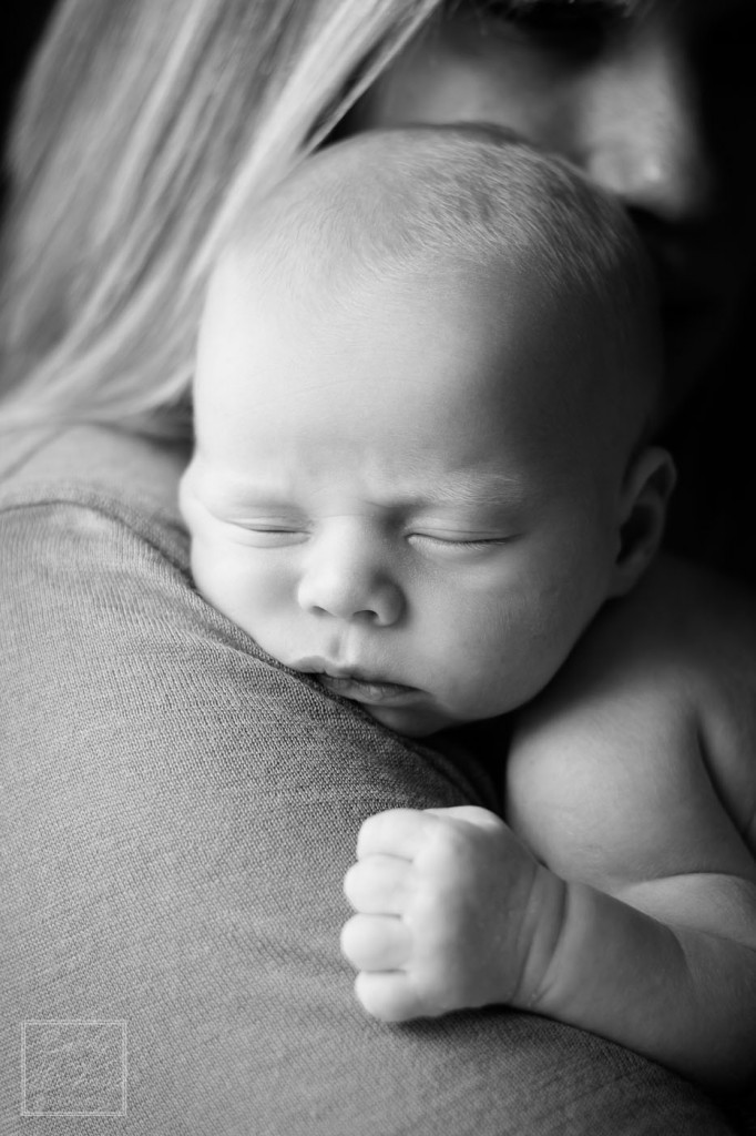 Portrait of a sleeping infant holding onto his mom