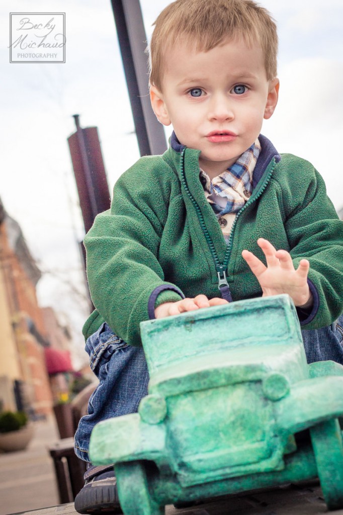Little boy playing with a car statue in Old Town Fort Collins