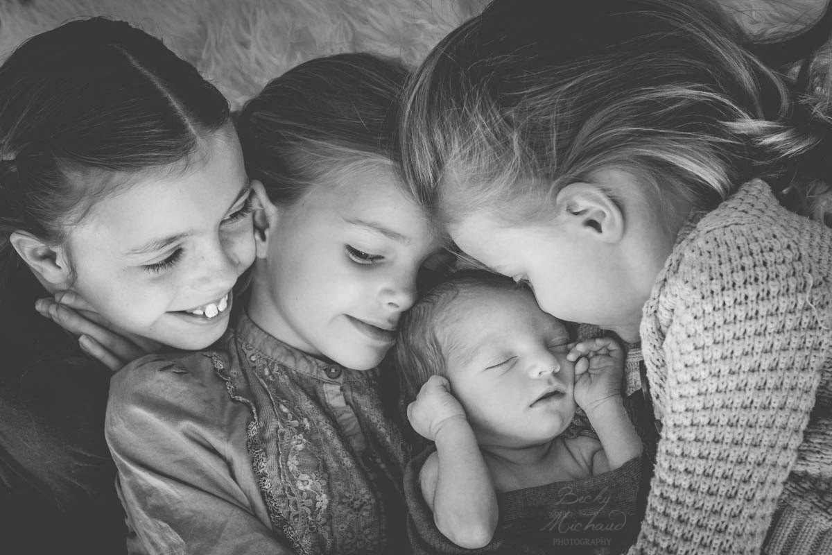 Three sisters admire their newborn baby brother 