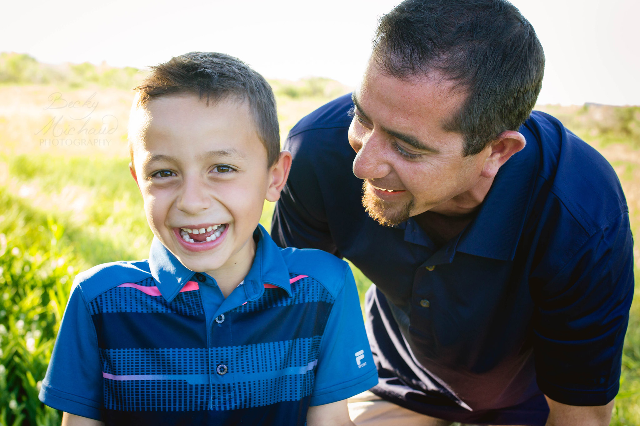 A boy and his father laughing in a field in Loveland Colorado