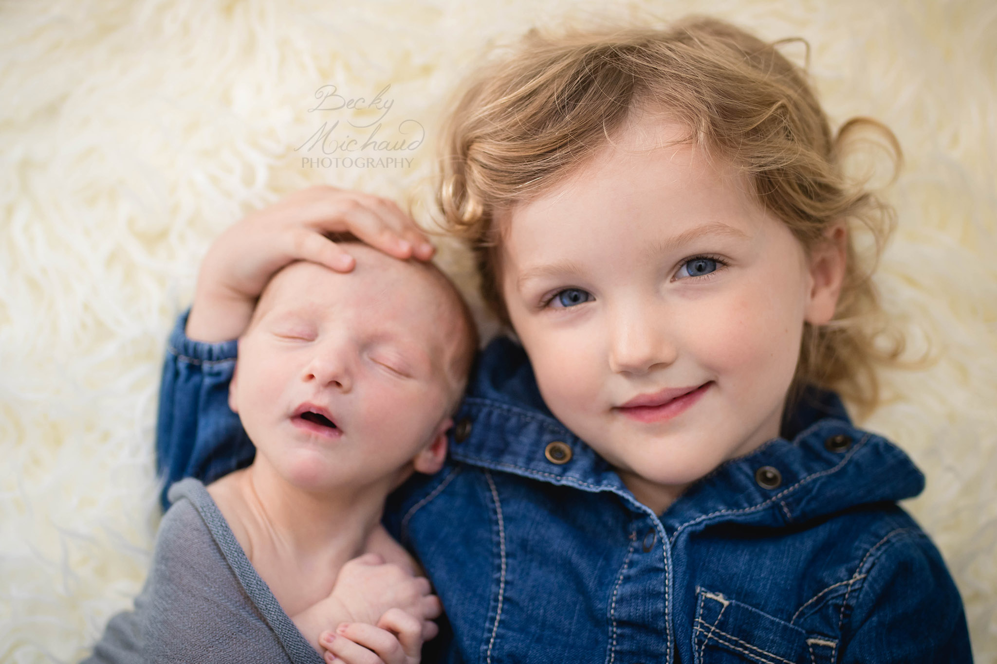 Big sister poses with her baby brother during his newborn photo session in their Fort Collins home