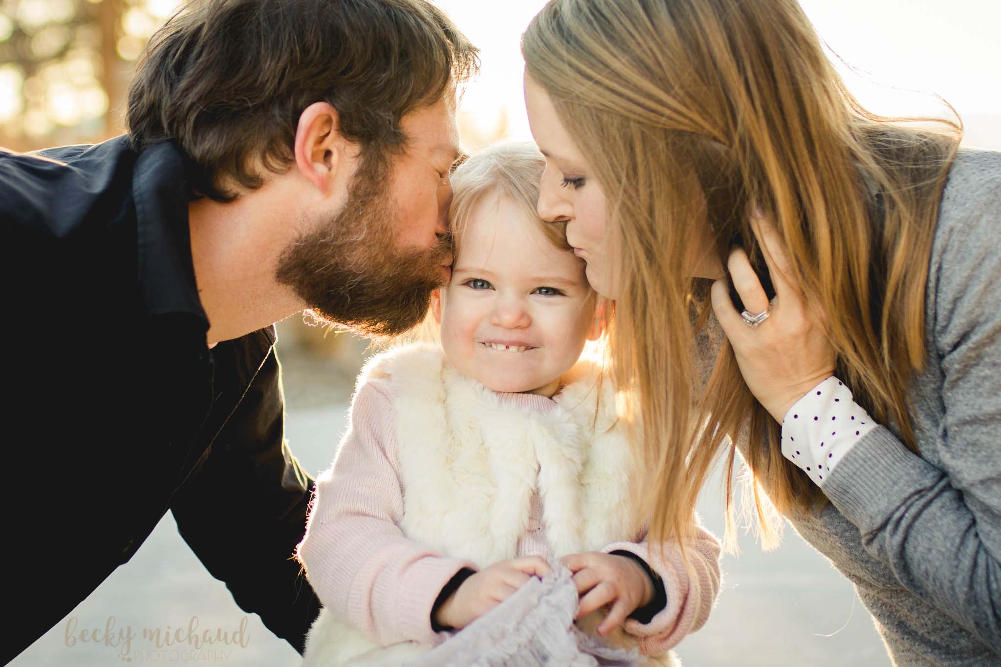 parents kissing their two year old daughter during a photo session in Fort Collins, Colorado