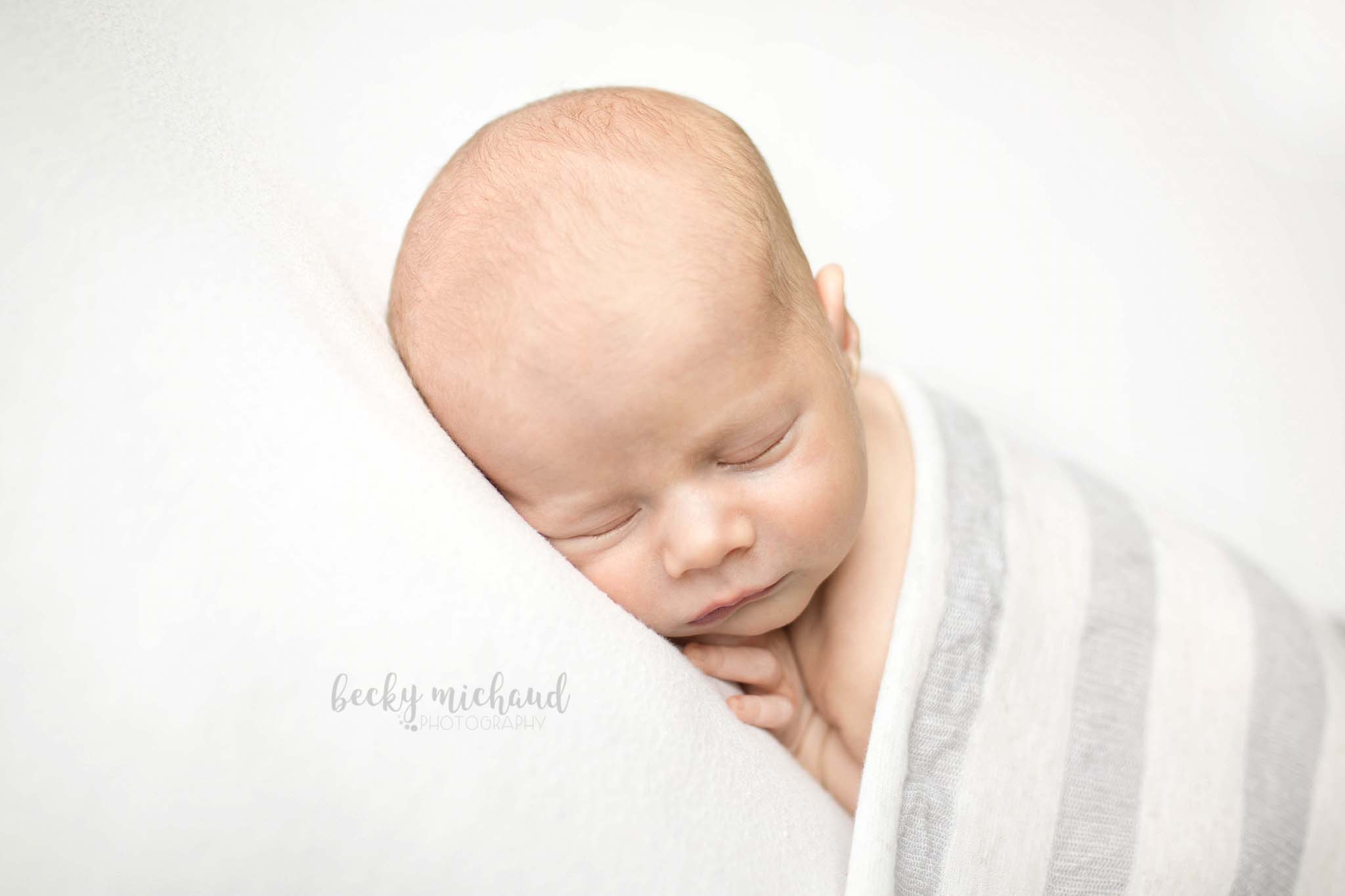 baby boy tucked under a striped blanket in Northern Colorado for a baby photo 