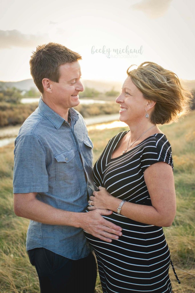 A couple poses for their maternity photo session at sunset 