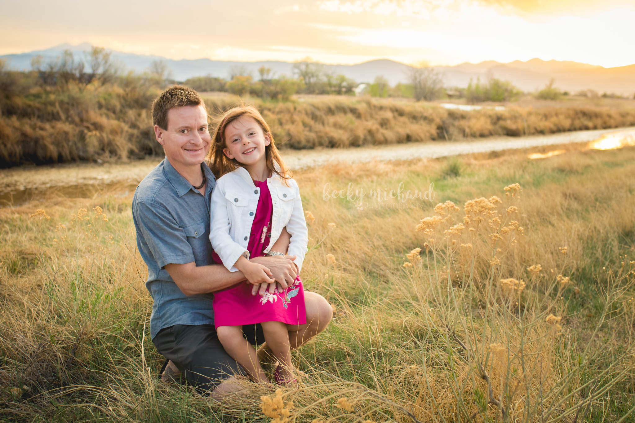 a father and his daughter pose in a field in front of the mountains  for their photo session in Loveland, Colorado