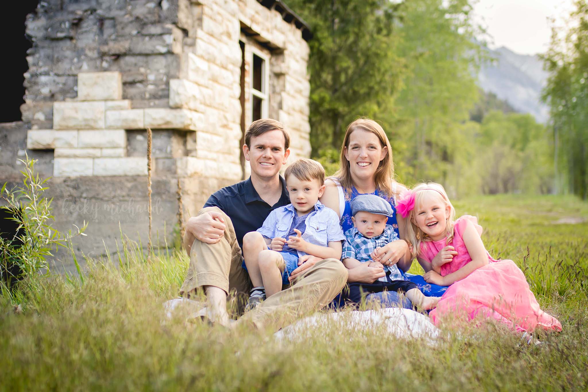 A family of five poses by an old building during their family photo session at the old marble mill