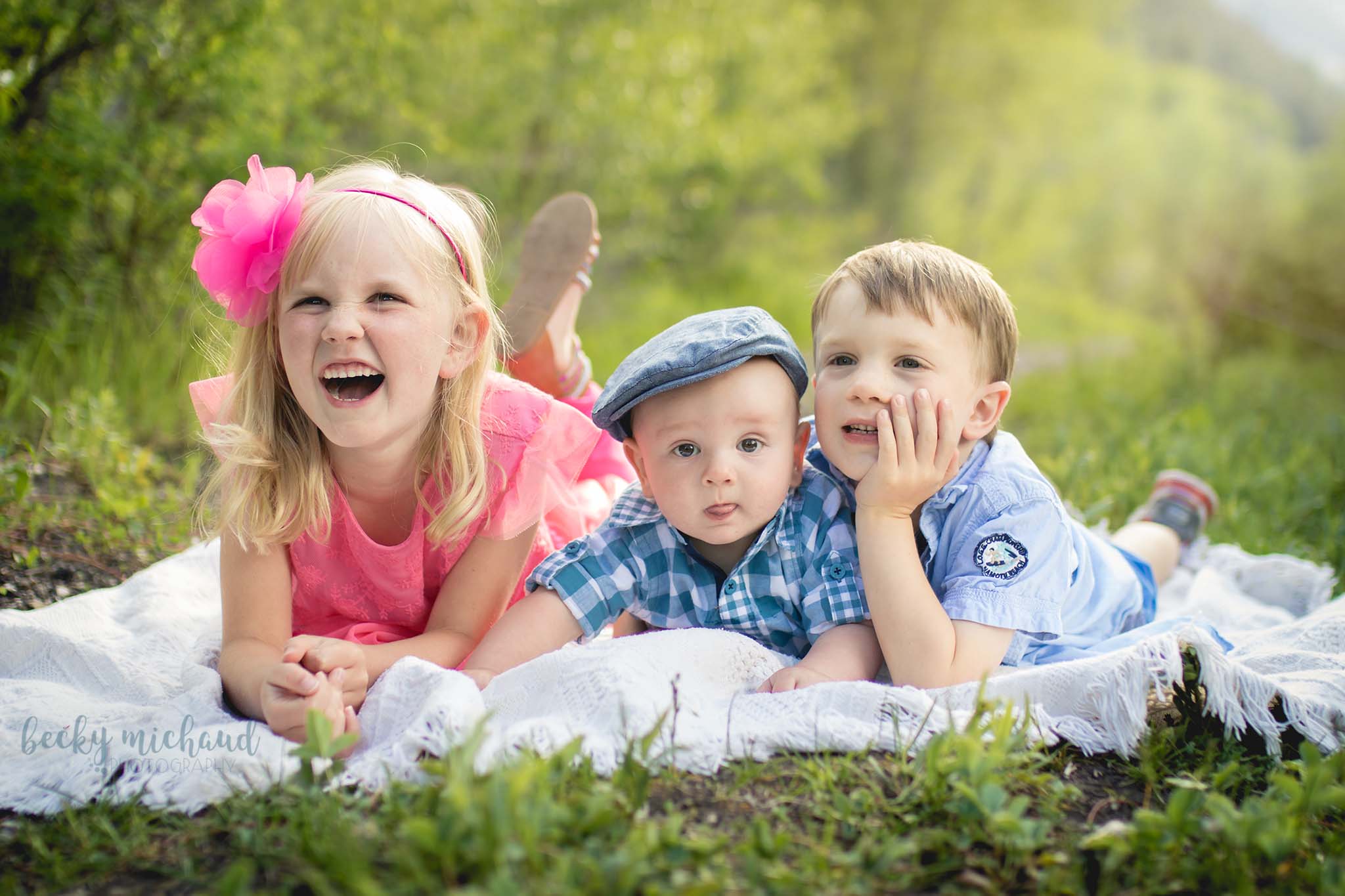 Siblings cuddle and laugh on a blanket during their photography session in the mountains of Colorado