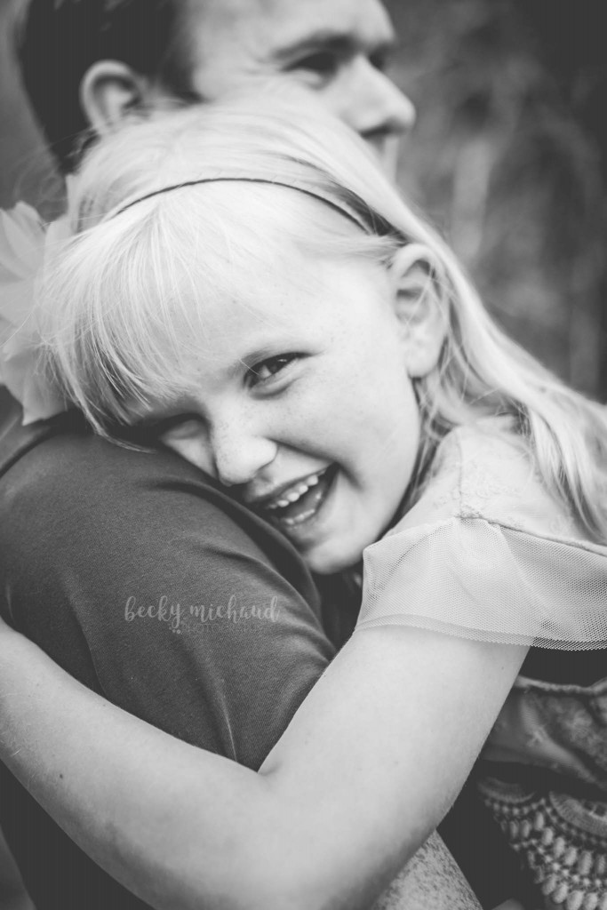 little girl laughing and hugging her dad