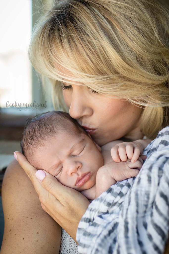 A mom kisses her baby boy during their in home newborn photo session in Berthoud Colorado