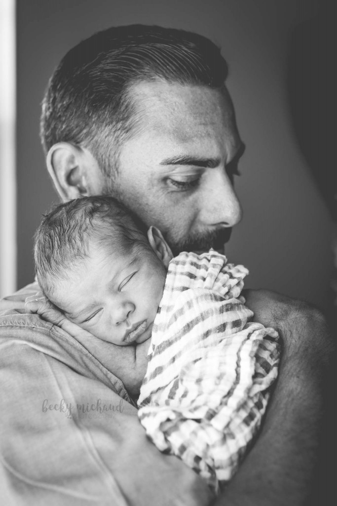black and white photo of a dad holding his sleeping baby
