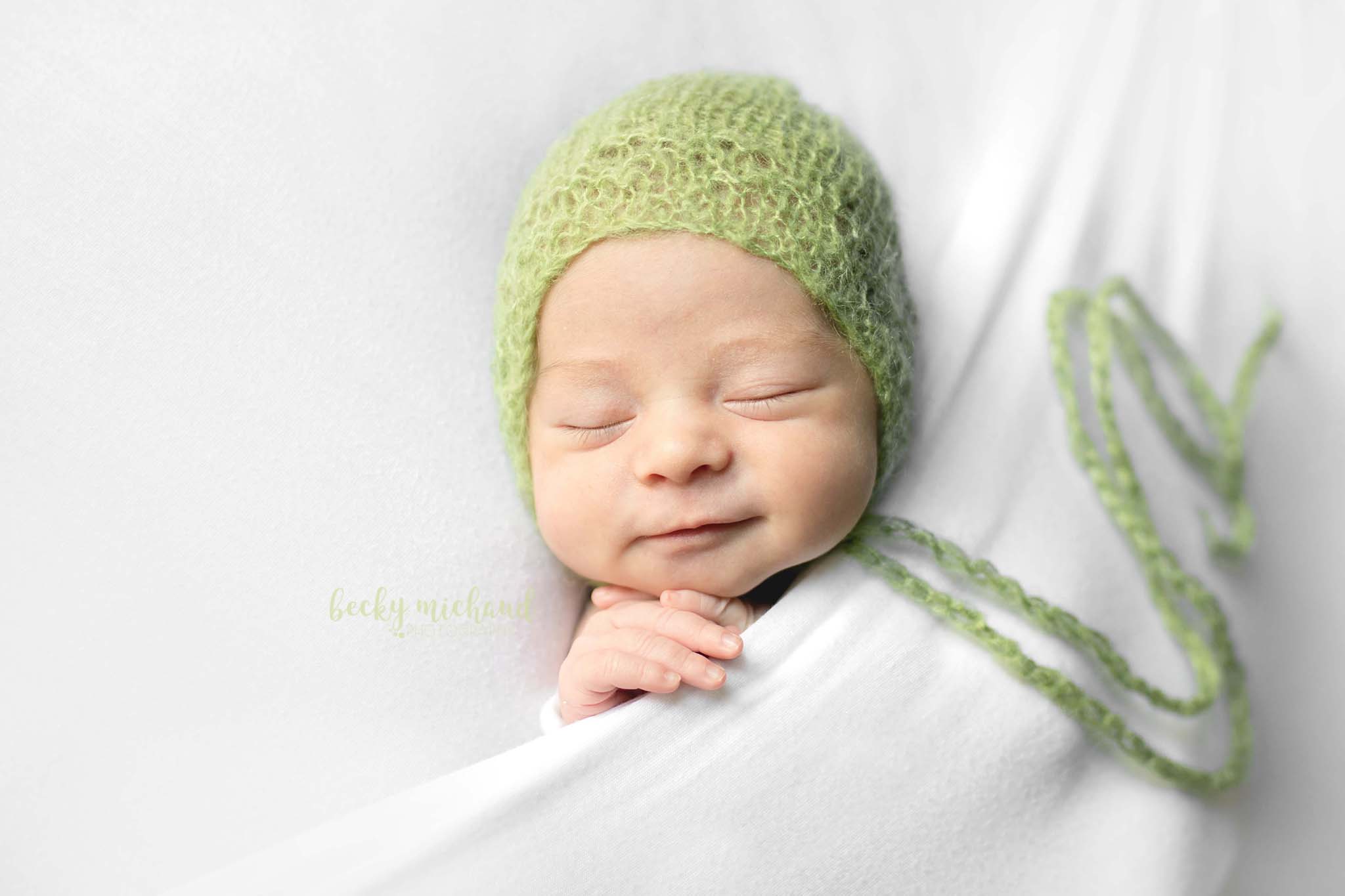 Baby girl wearing a green bonnet in a simple newborn portrait