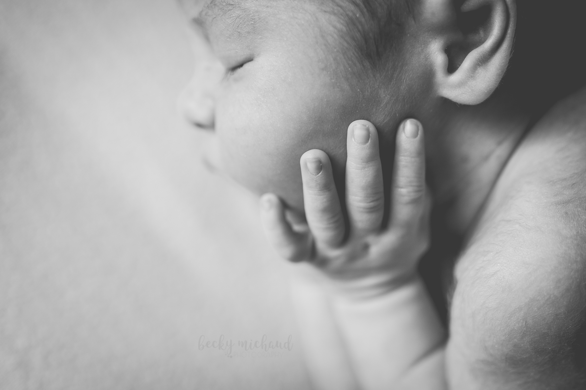 macro shot of newborn hand on cheek
