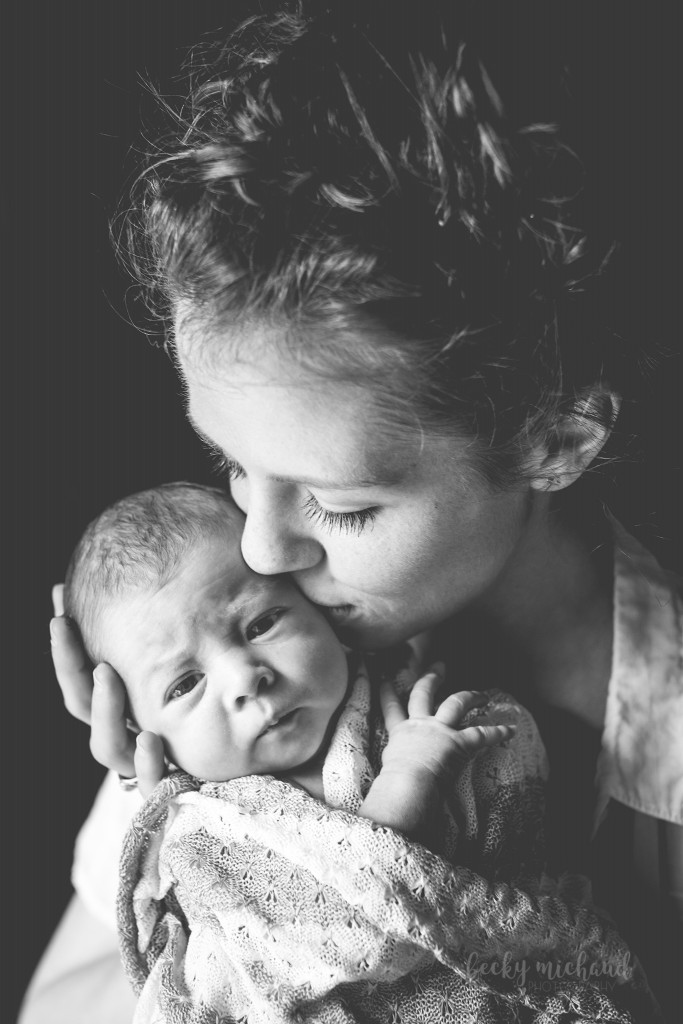 A black and white portrait of a mom kissing her baby during her newborn photo session