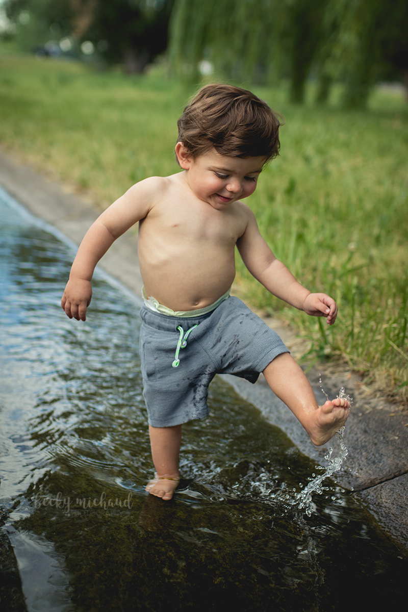 A toddler boy kicking and splashing in the water