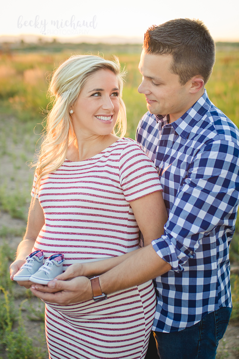 Expectant parents hold their baby's shoes during their maternity photo session with Becky Michaud, Fort Collins photographer