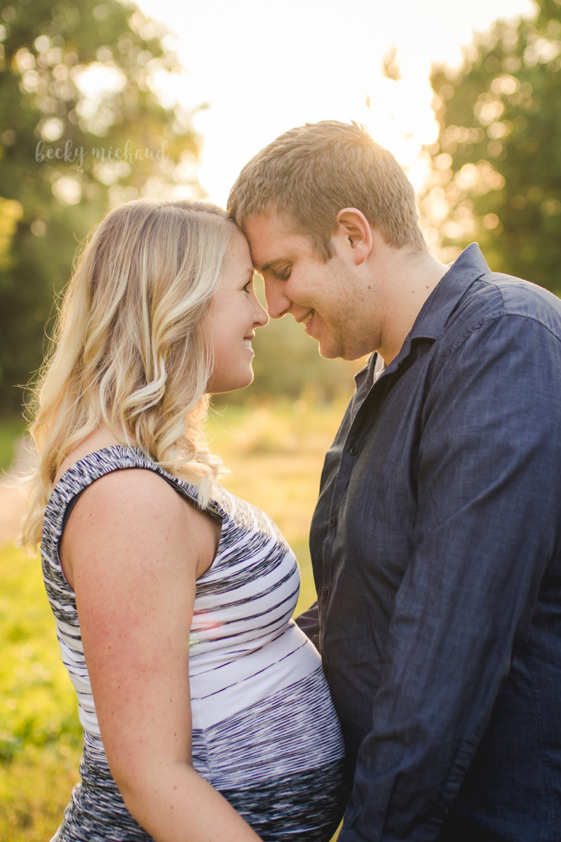 An expecting mom and dad share a quiet moment during their maternity photo session at Legacy Park in Fort Collins