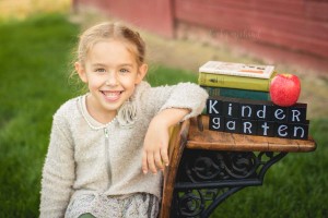 A girl sits on an antique school desk for her back to school photo
