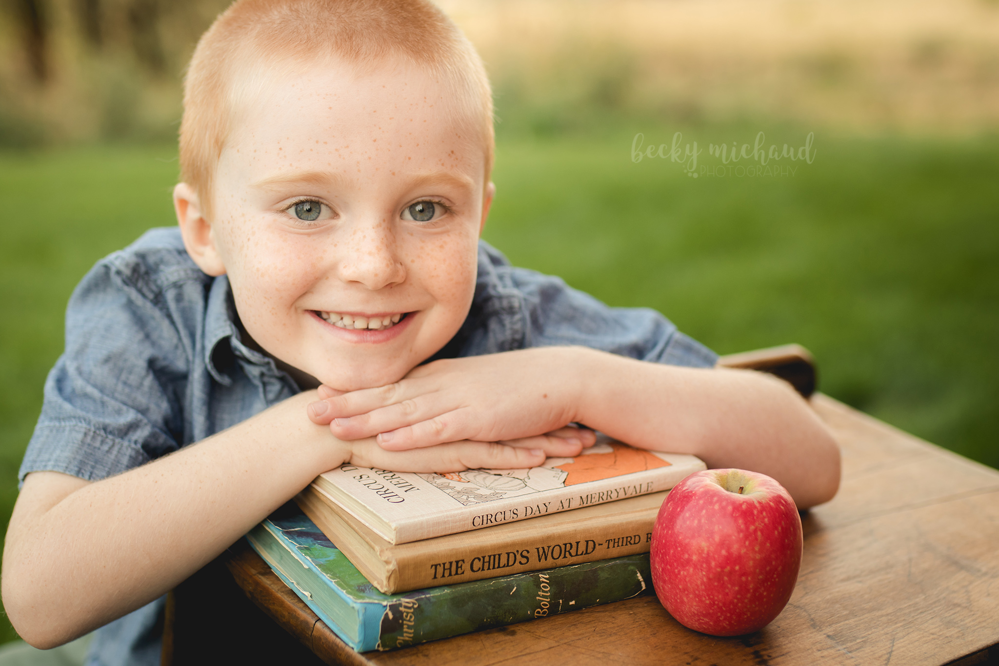 A boy rests his head on a stack of books