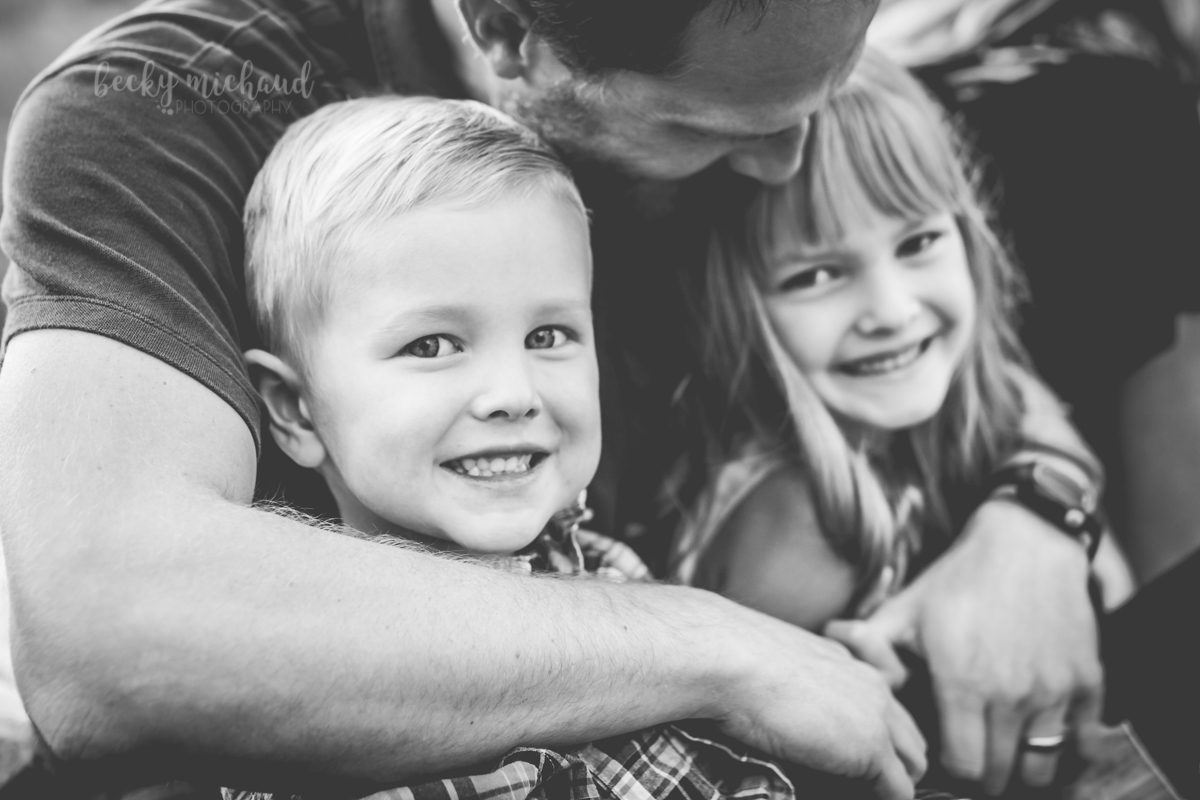 Black and white portrait of a dad hugging his two kids at a Park in Fort Collins, CO