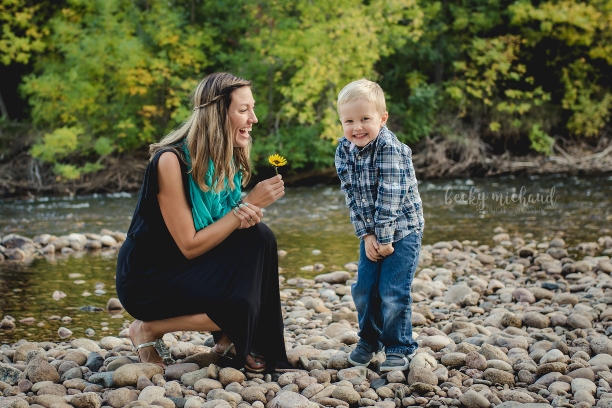 A boy smiles after giving his mom a flower during their Northern Colorado family photo session