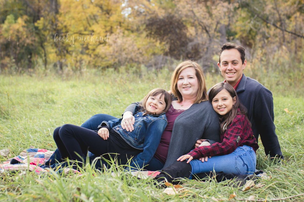 A family of four poses in a field during their Fort Collins photo session with Becky Michaud