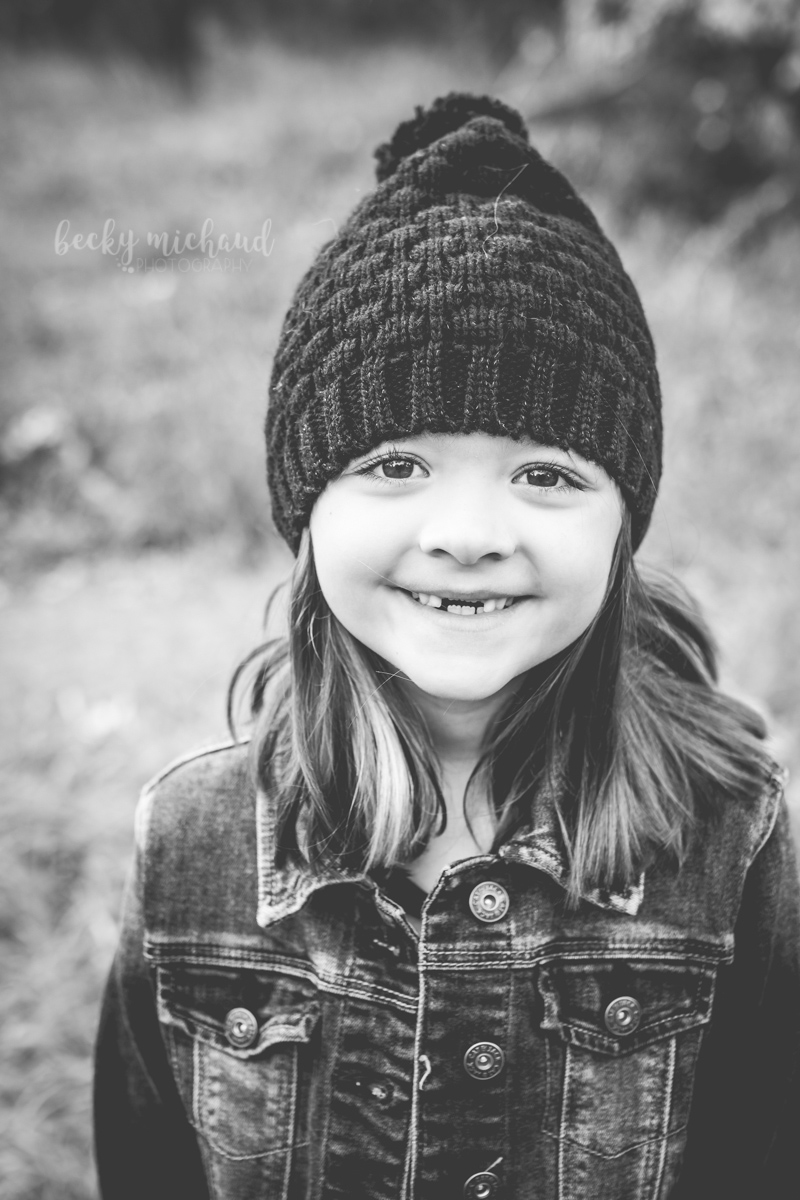Black and white portrait of a little girl with missing front teeth and a stocking cap