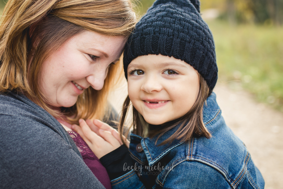 A girl cuddles with her mom during their family photo session in Northern Colorado