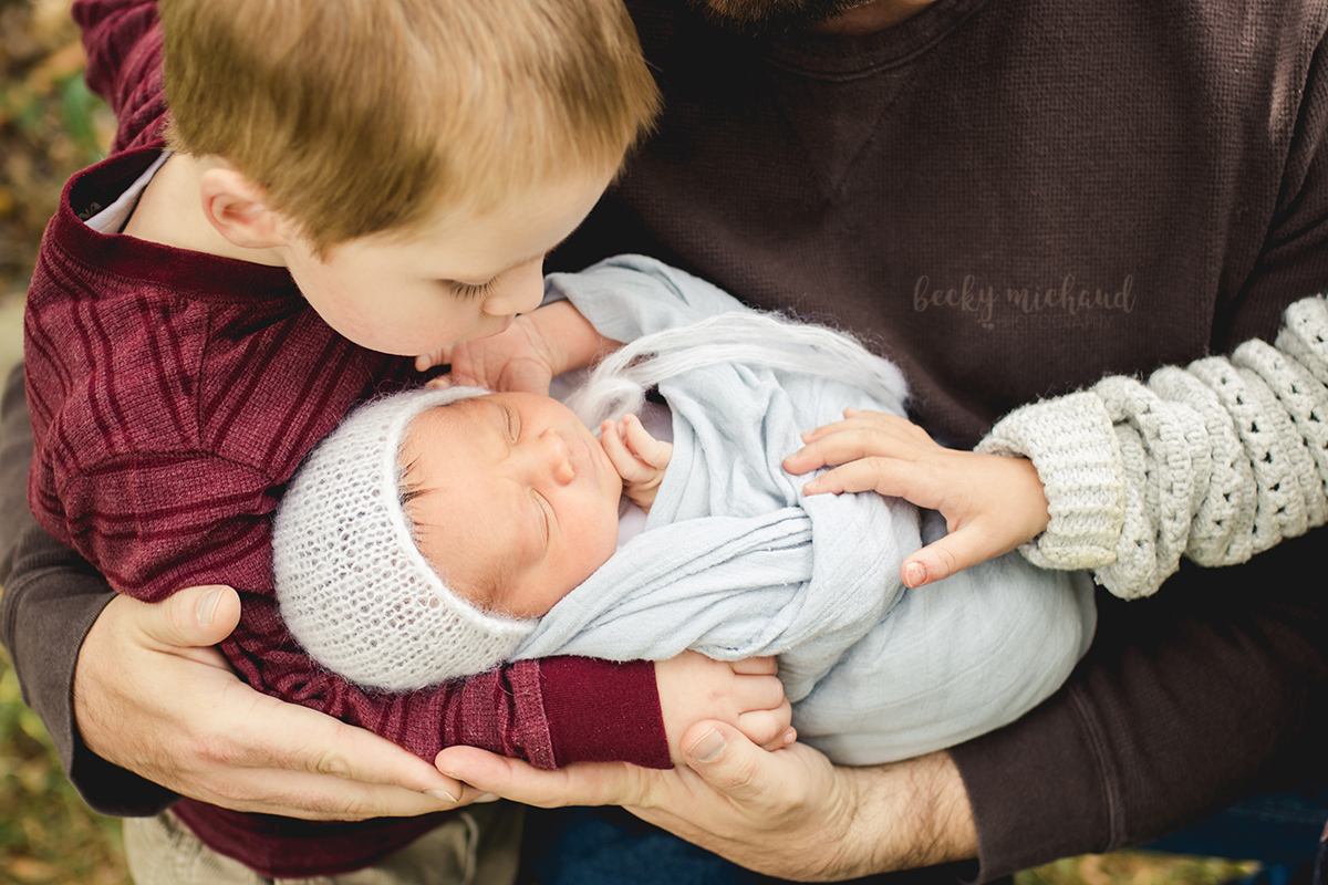 A little boy kisses his newborn baby sister during their Northern Colorado family photo session