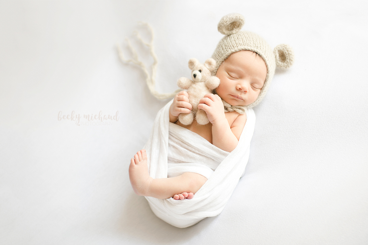 Newborn photo featuring a baby girl with teddy bear accessories