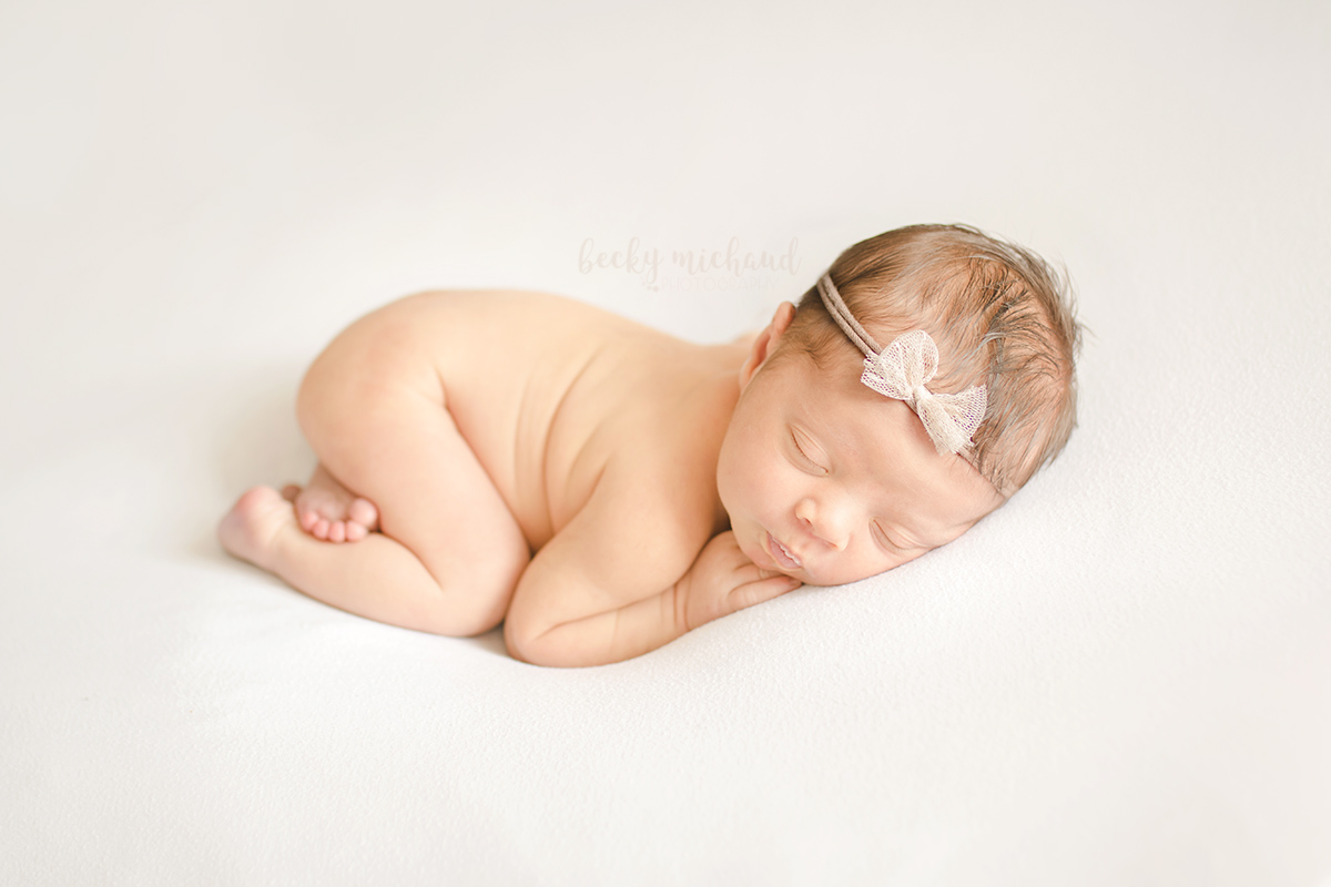 Simple minimalist newborn photography of a baby girl wearing a tan bow headband