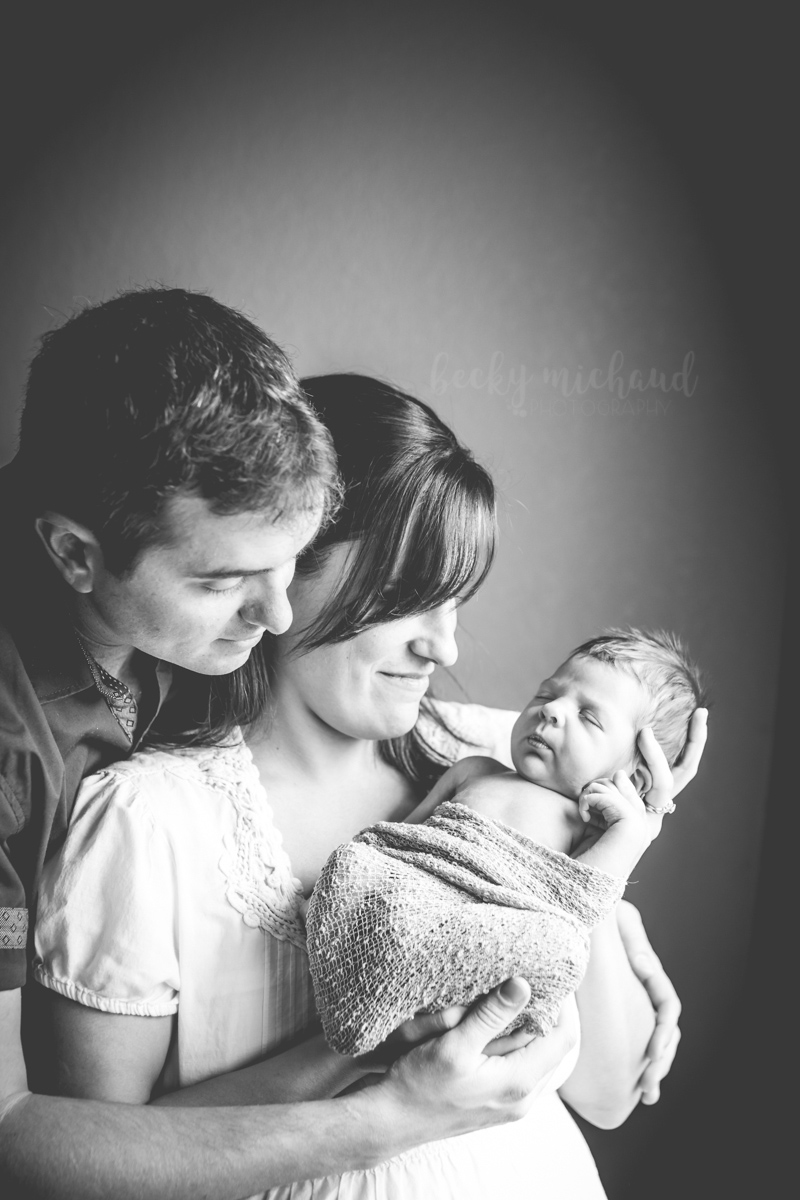 Proud parents gaze at their newborn baby during their in home newborn portrait session