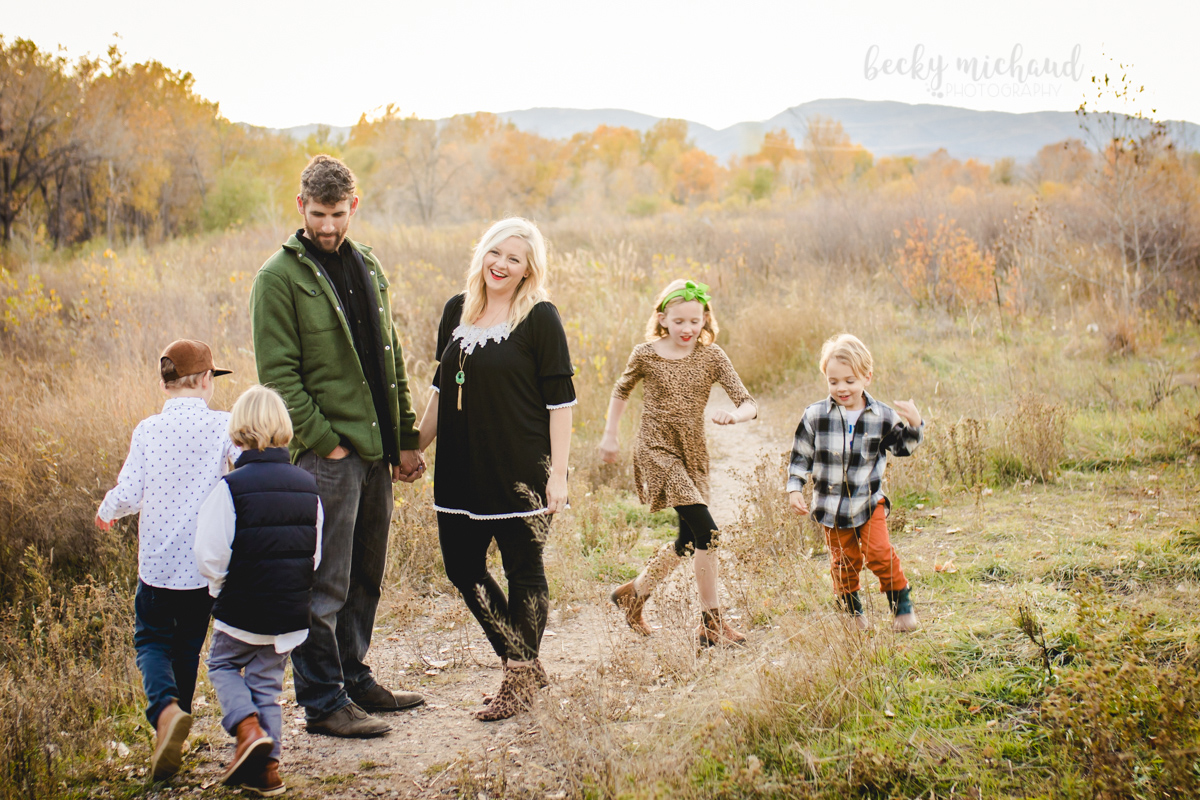 Four children run in a field in Fort Collins in the fall while their parents watch