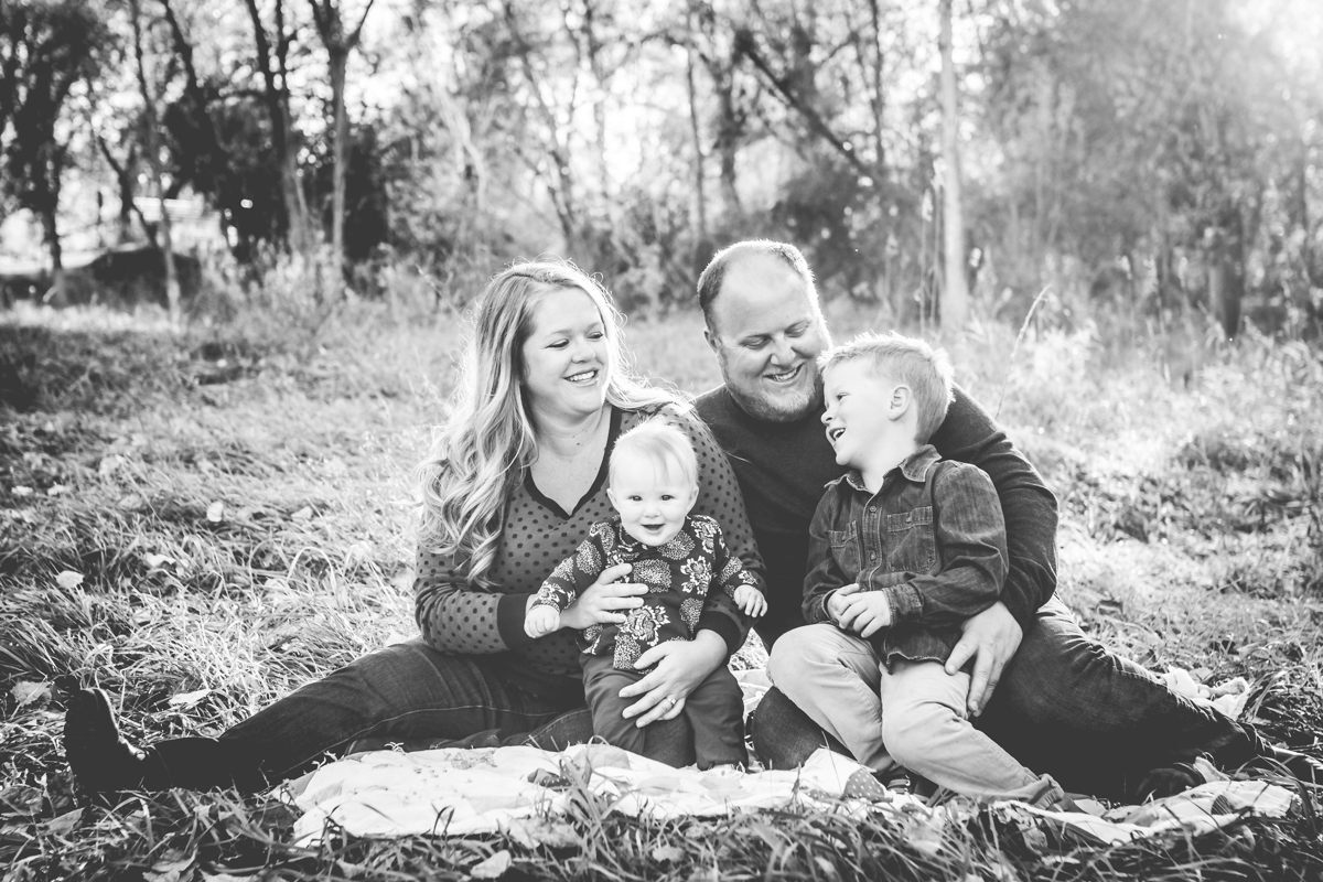 Black and white portrait of a family sitting in a wooded field at a Fort Collins natural area