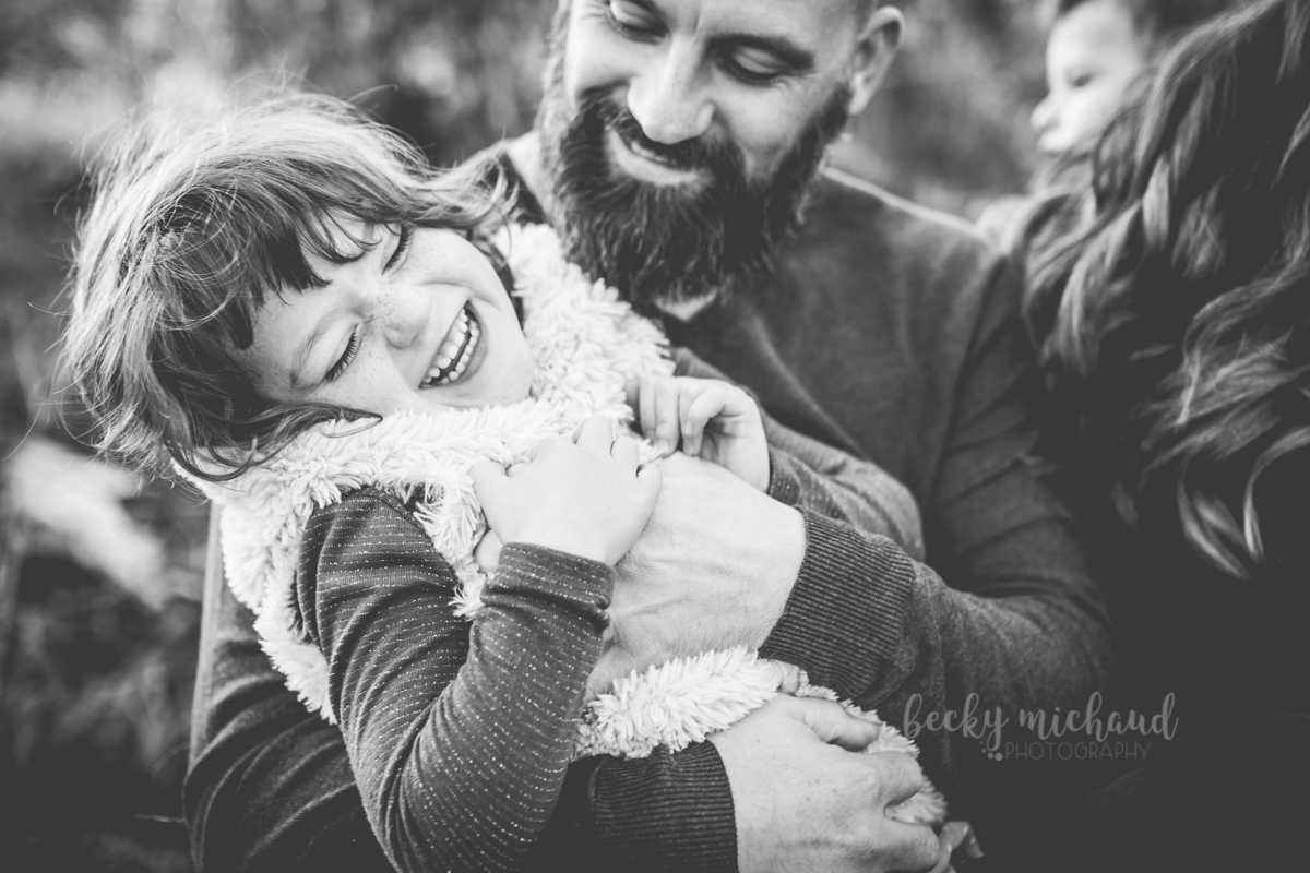 Black and white portrait of a dad tickling his daughter