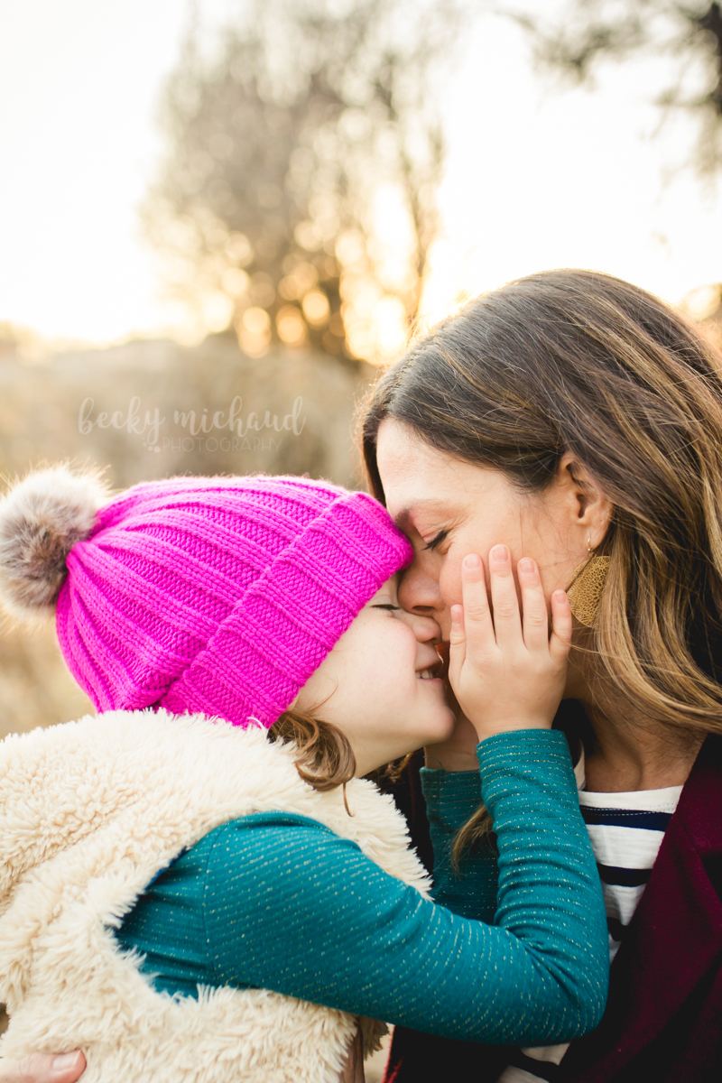 A little girl holds her moms cheeks as they share a tender moment during their family photography session