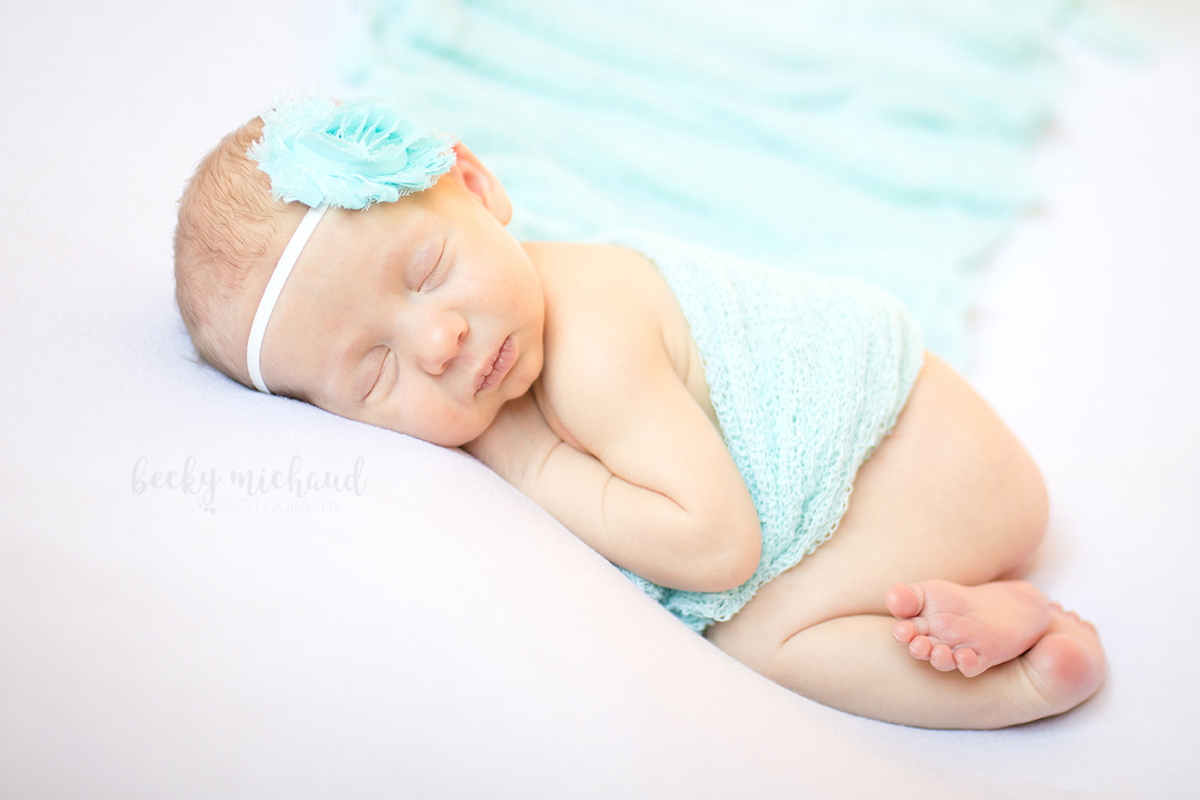 In home newborn session in Fort Collins Colorado includes a photo of a baby girl with a blue headband and blanket
