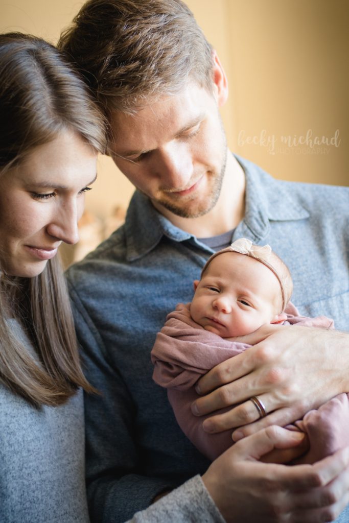 A new little family of three poses for their newborn photos in their Fort Collins home