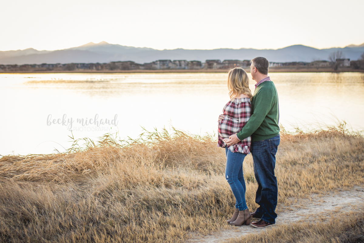 Maternity photo of a couple watching the sun set over the lake and mountains in Loveland, Colorado