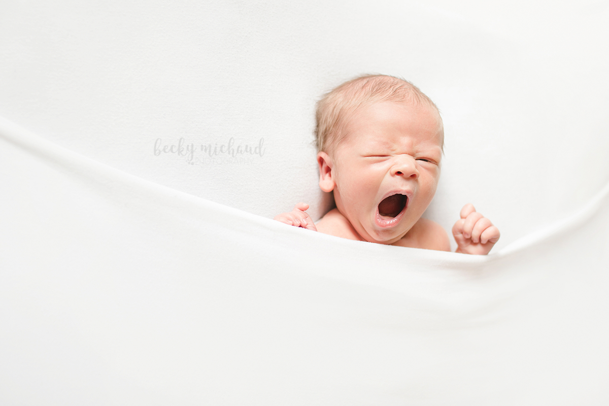 Baby boy yawns during his newborn photo session