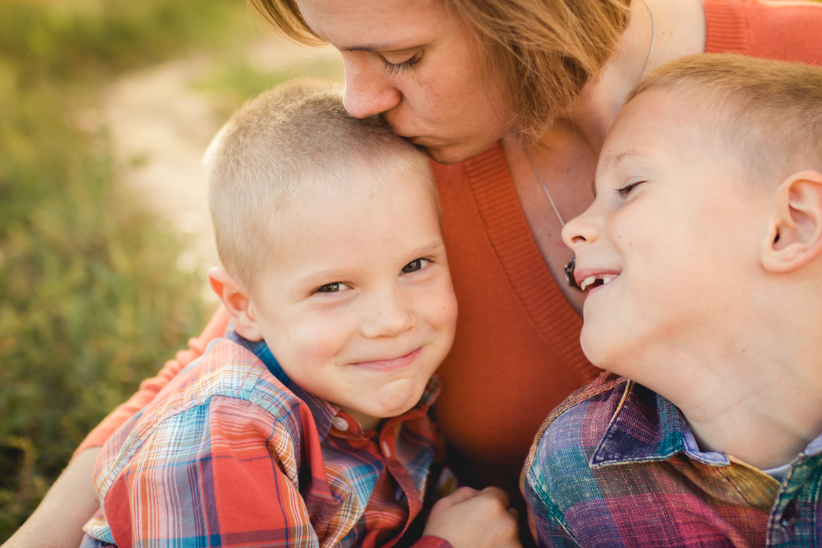 A mom cuddles and kisses her boys during their Fort Collins family photo session
