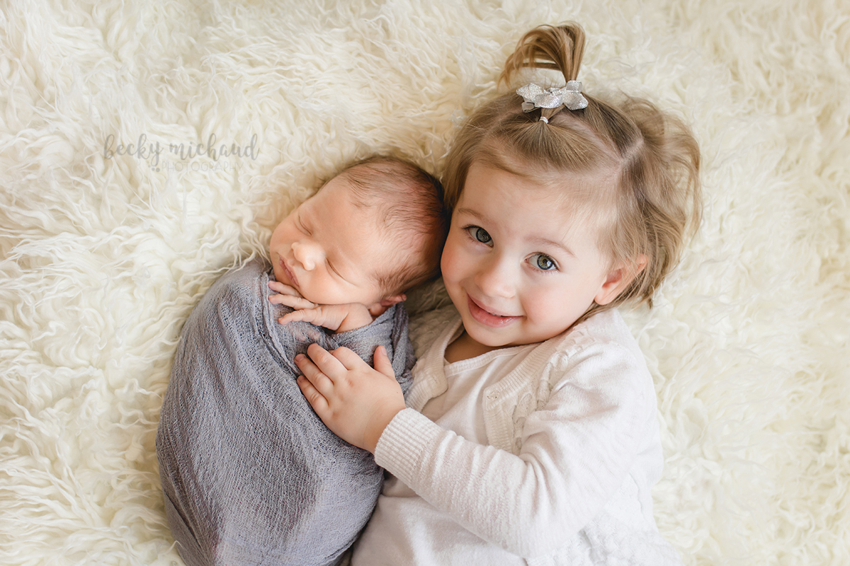 A new big sister snuggles up to her newborn baby brother during their Northern Colorado photo session