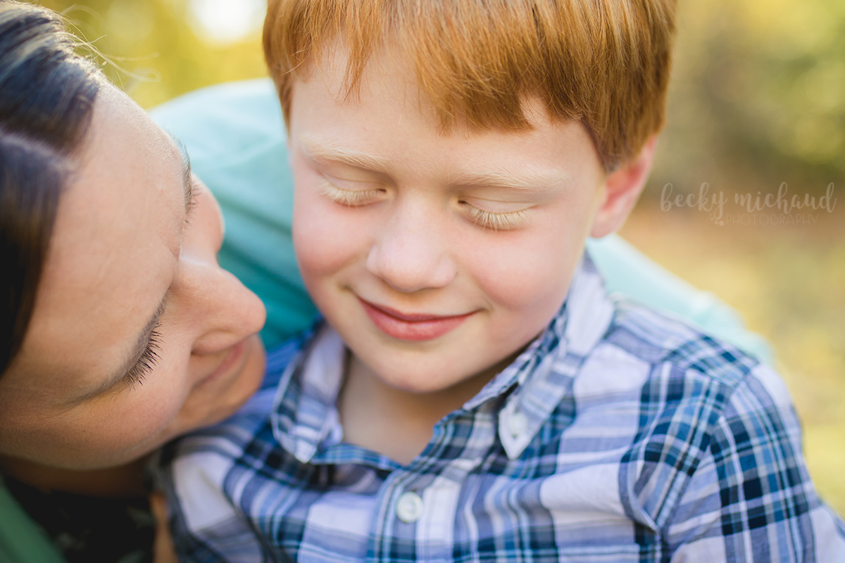 A red haired boy shares a quiet moment with his mom during their family photo session at a Fort Collins natural area