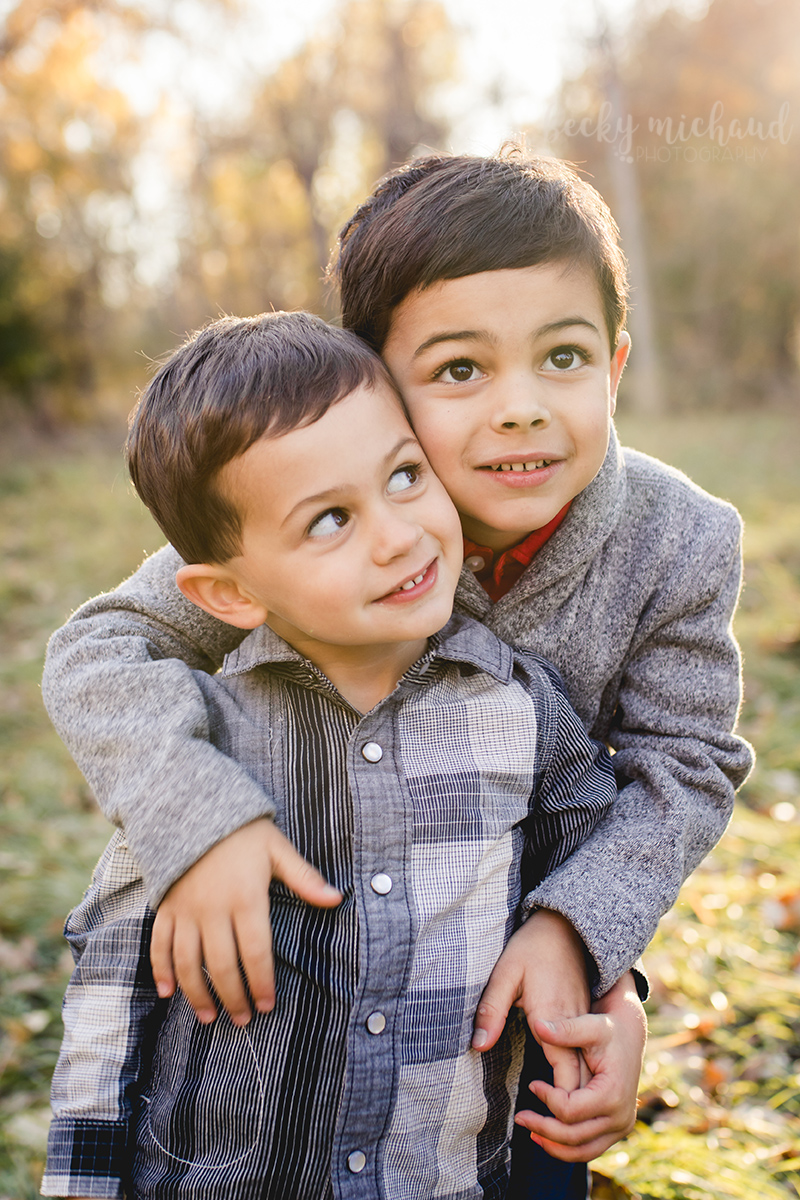 A little brother looks up at his big brother during their family photo session