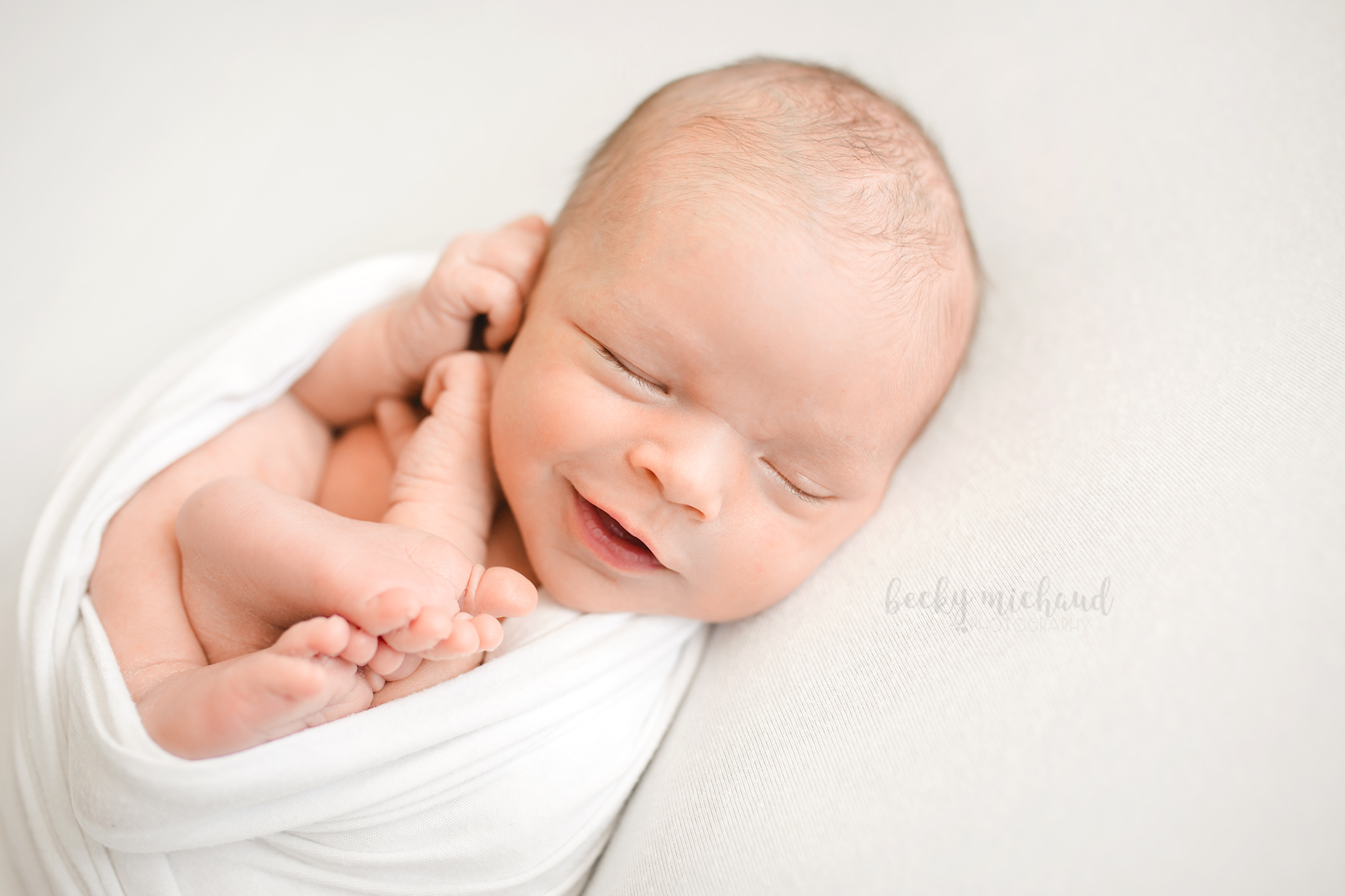 Simple organic newborn portrait of a baby boy smiling