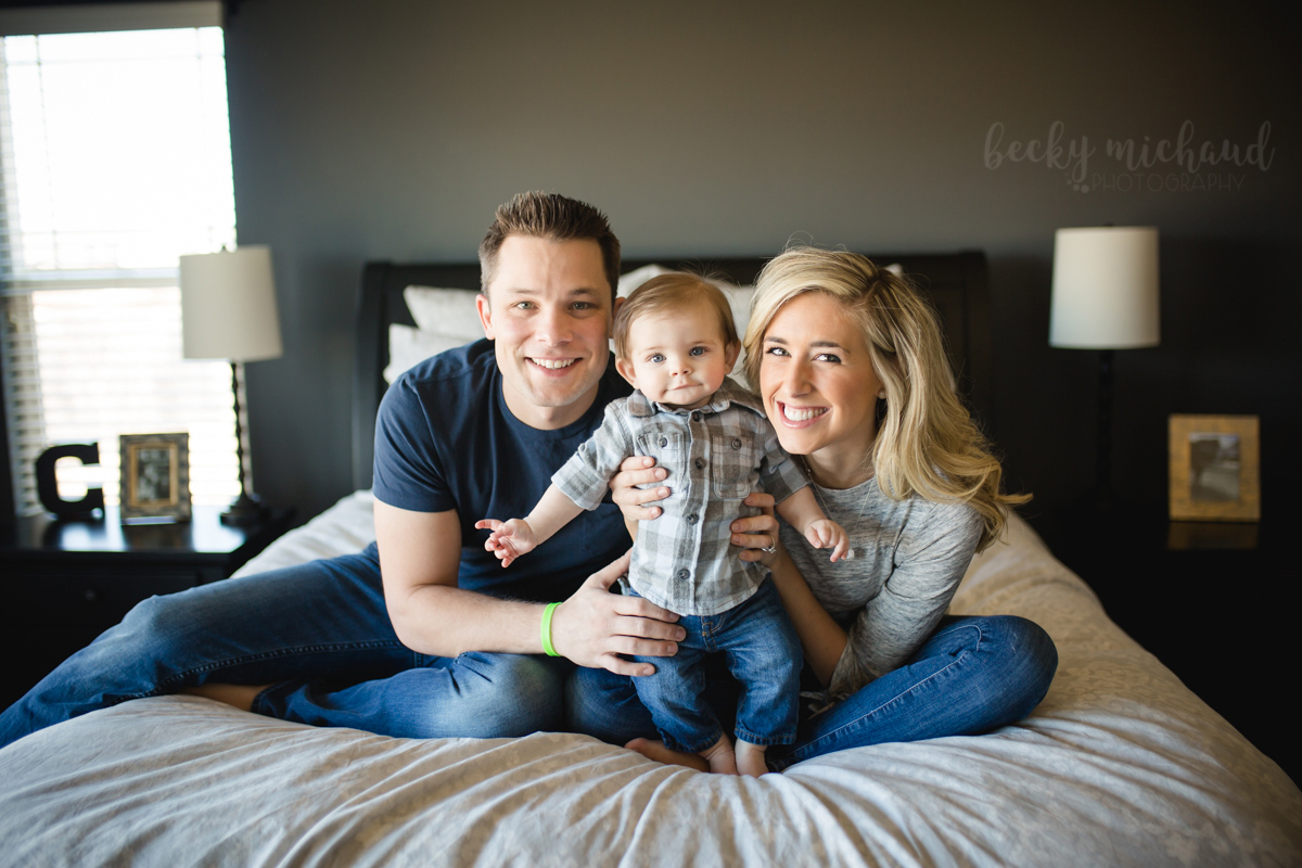 A family of three poses on their bed during their in home Colorado lifestyle photo session