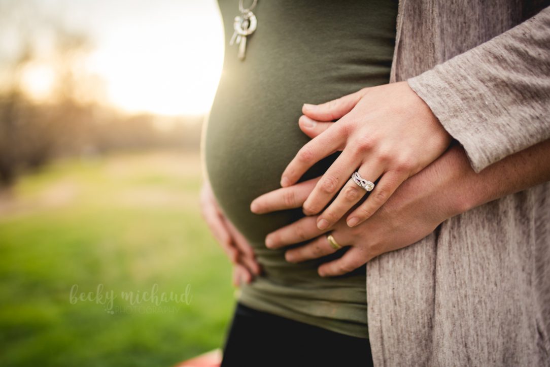 Close up of a husband and wife holding hands during their pregnancy photo shoot