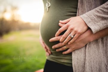Close up of a husband and wife holding hands during their pregnancy photo shoot