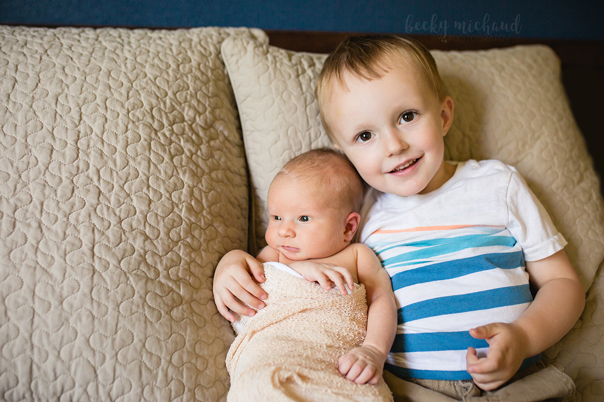 A big brother holds his newborn brother in their Fort Collins home during their in home newborn photo session
