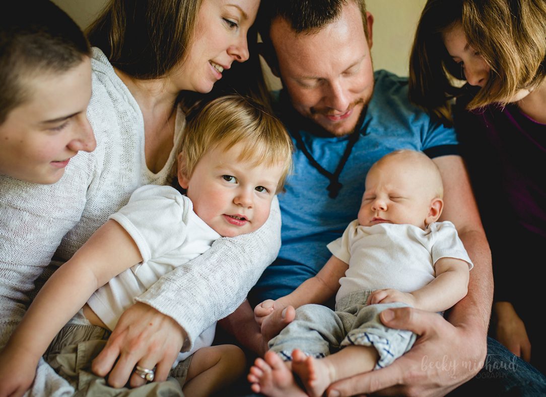 A family of six snuggles together with their new baby during their photography session in their Windsor Colorado home