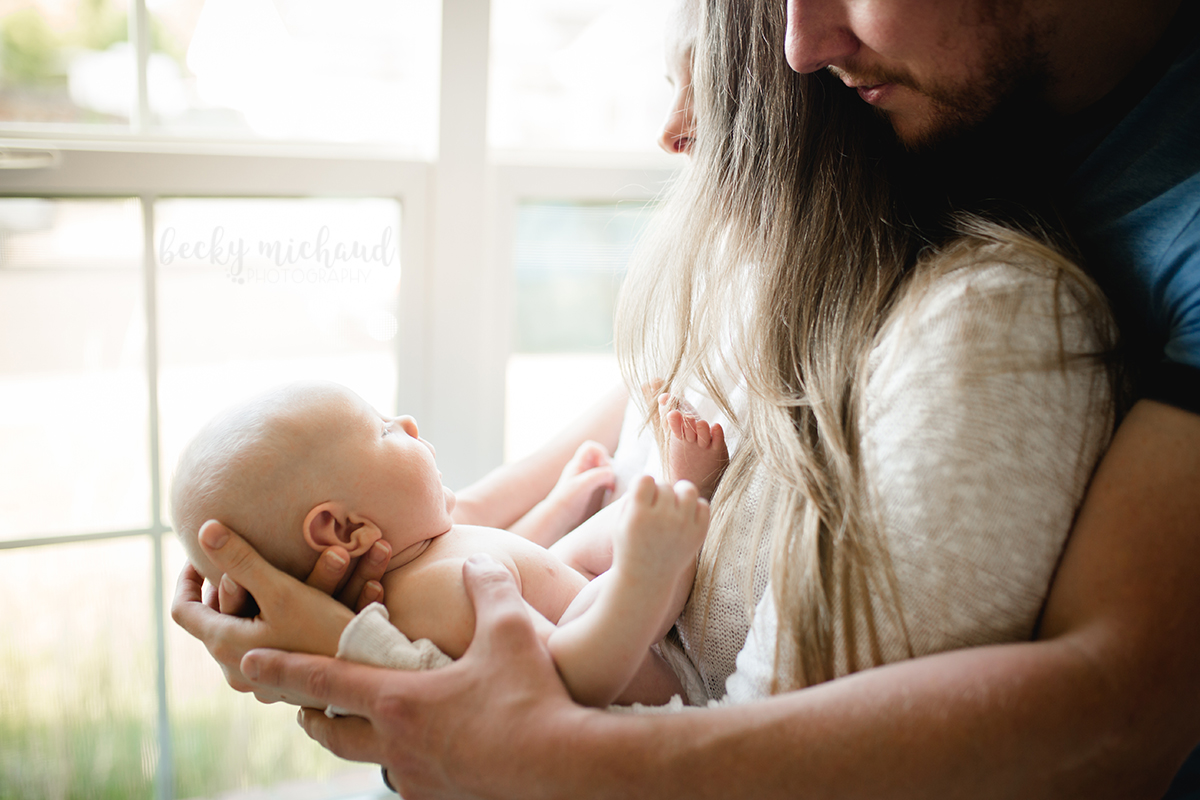 Backlit photo of a mom and dad holding their baby boy in their Northern Colorado home